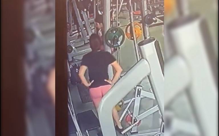 Chica fitness haciendo sentadillas con la barra en la máquina